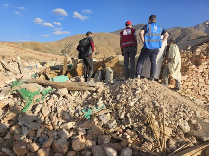 Islamic Relief staff members standing in rubble from Earthquake