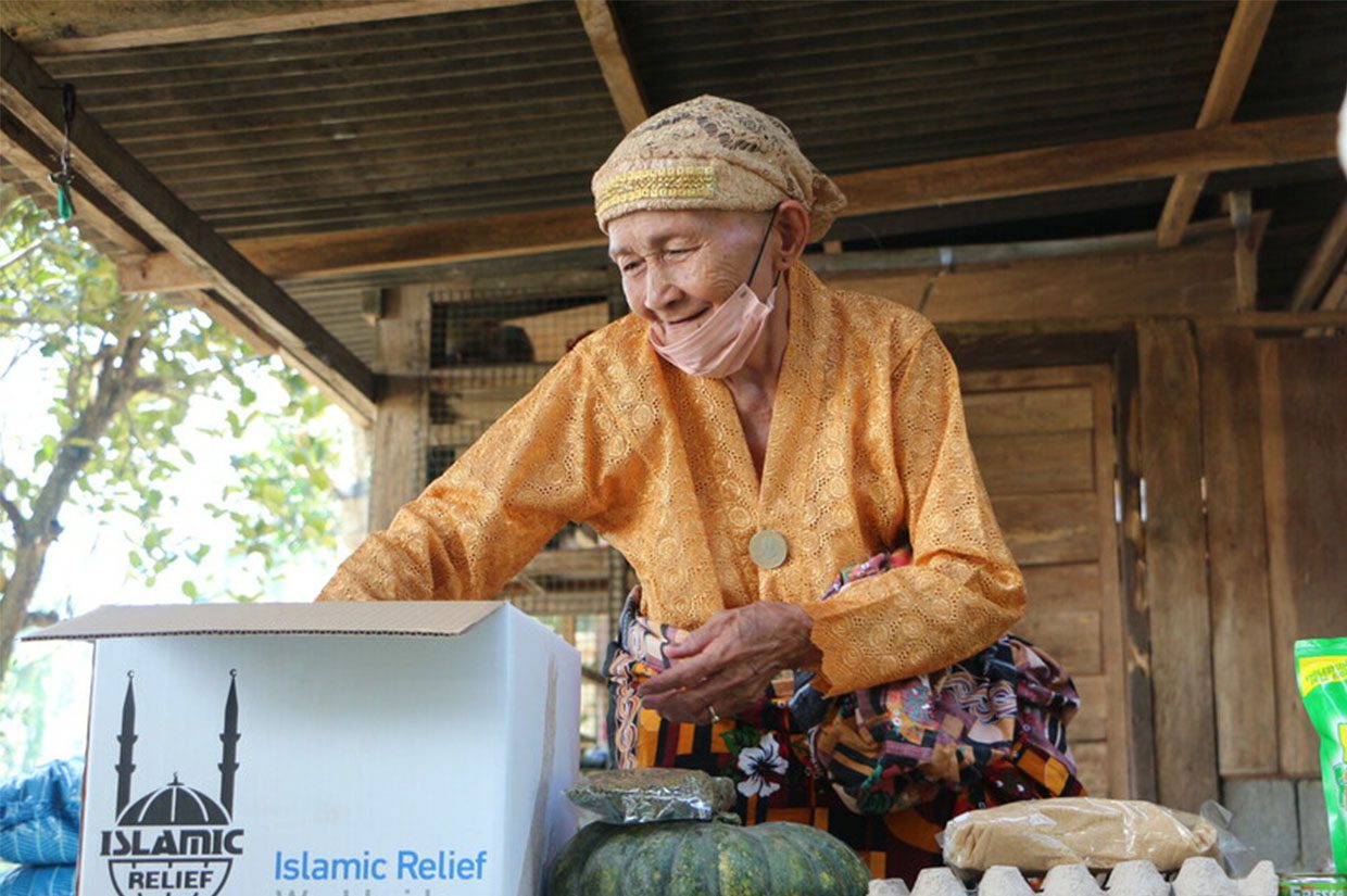 elderly women from the phillipinnes smiling while receiving food pack from islamic relief zakat beneficiaries