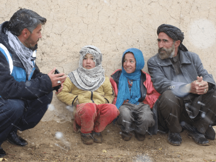Islamic relief aid worker speaking to a returning Afghan family