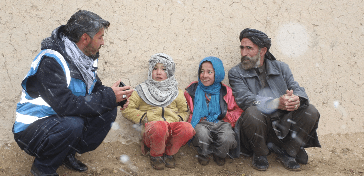 Islamic relief aid worker speaking to a returning Afghan family