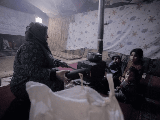 a syrian mother with her children sitting in a tent during the winter season